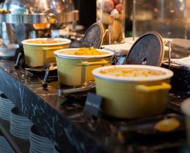Buffet with various dishes in yellow pots at Indian Naan Restaurant
