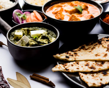 Indian thali with butter chicken, palak paneer, naan, and rice